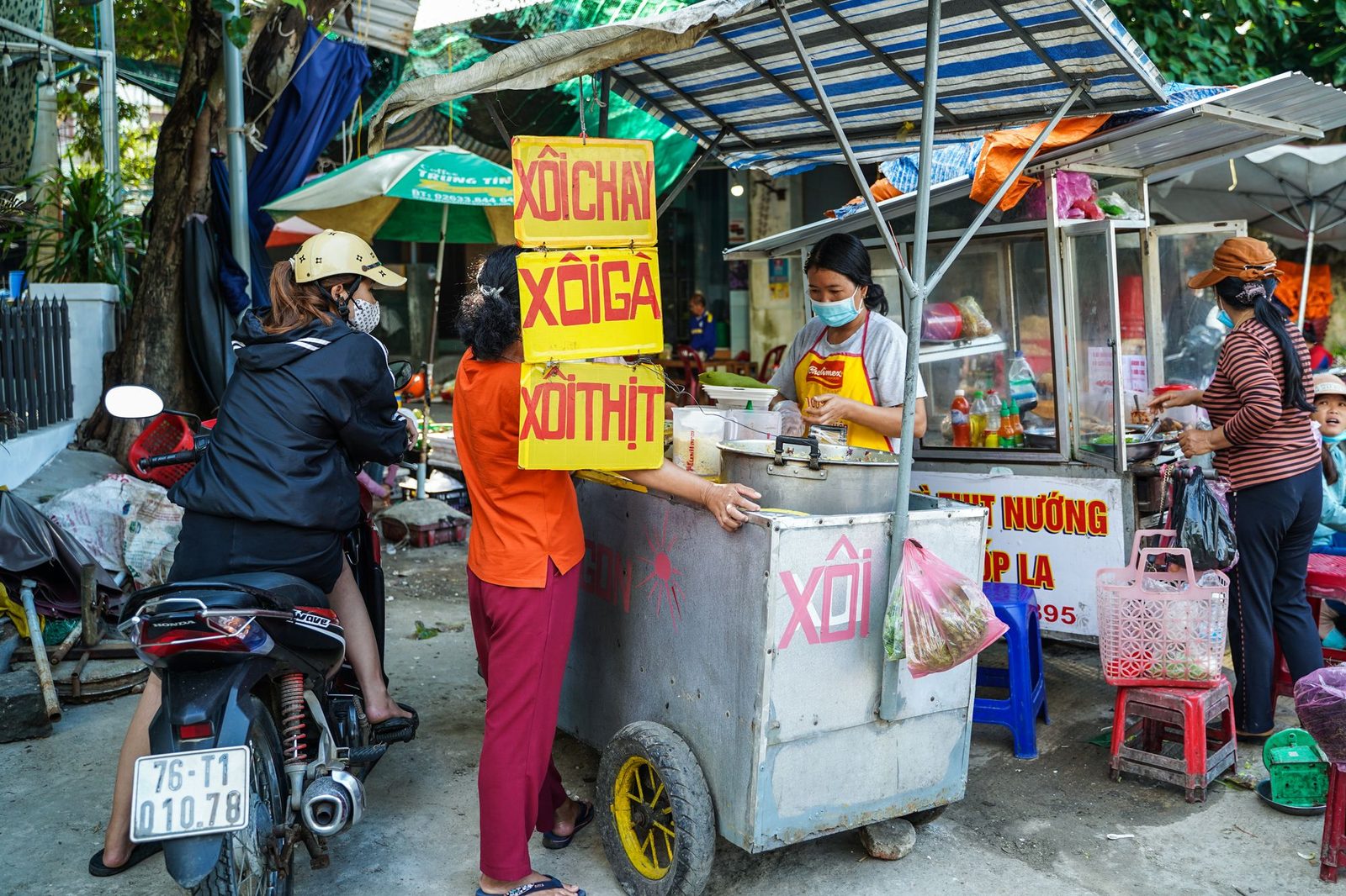 A street food vendor and a customer at a roadside cart